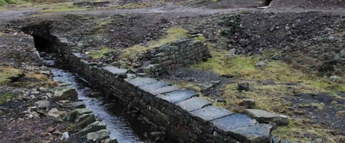 A stone pathway leading through a rocky landscape with a tunnel entrance in the distance.