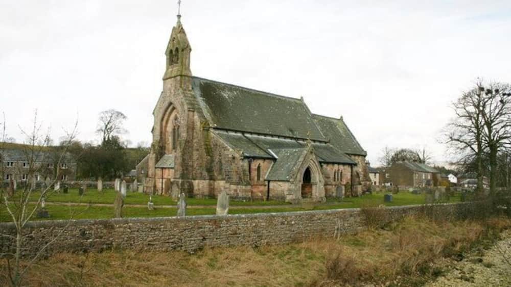 Une église historique, dotée d’un clocher imposant, entourée d’un cimetière et de murs en pierre.