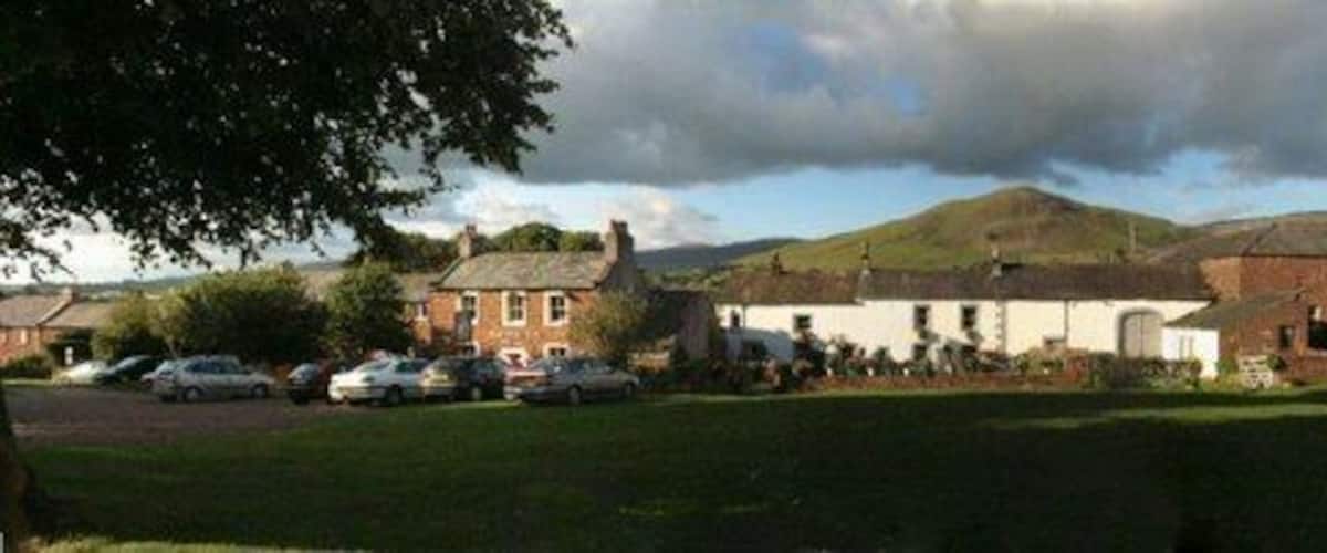 A rural village with houses, a grassy field, and a hill in the background.