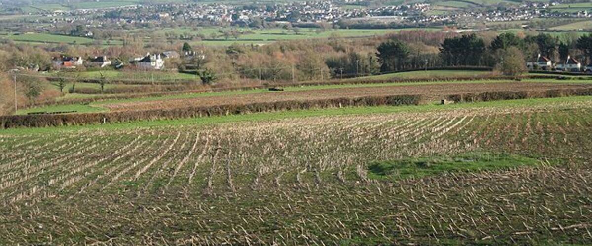 A rural landscape with fields, a distant town, and rolling hills.