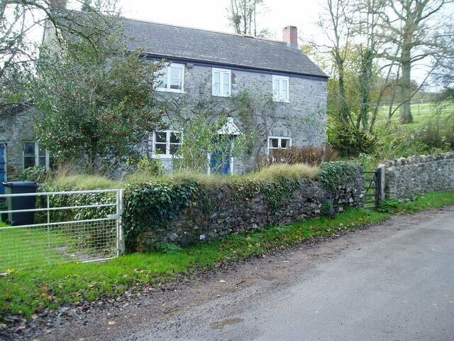 A stone house with a stone wall and a metal gate.