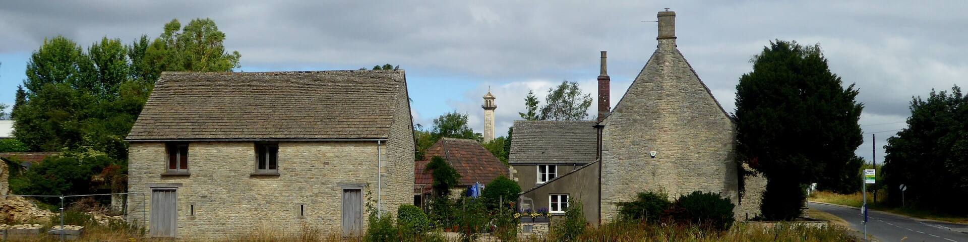 A rural village with stone houses, a church steeple, and a road.
