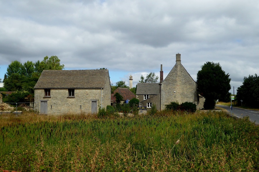 A rural village with stone houses, a church steeple, and a road.