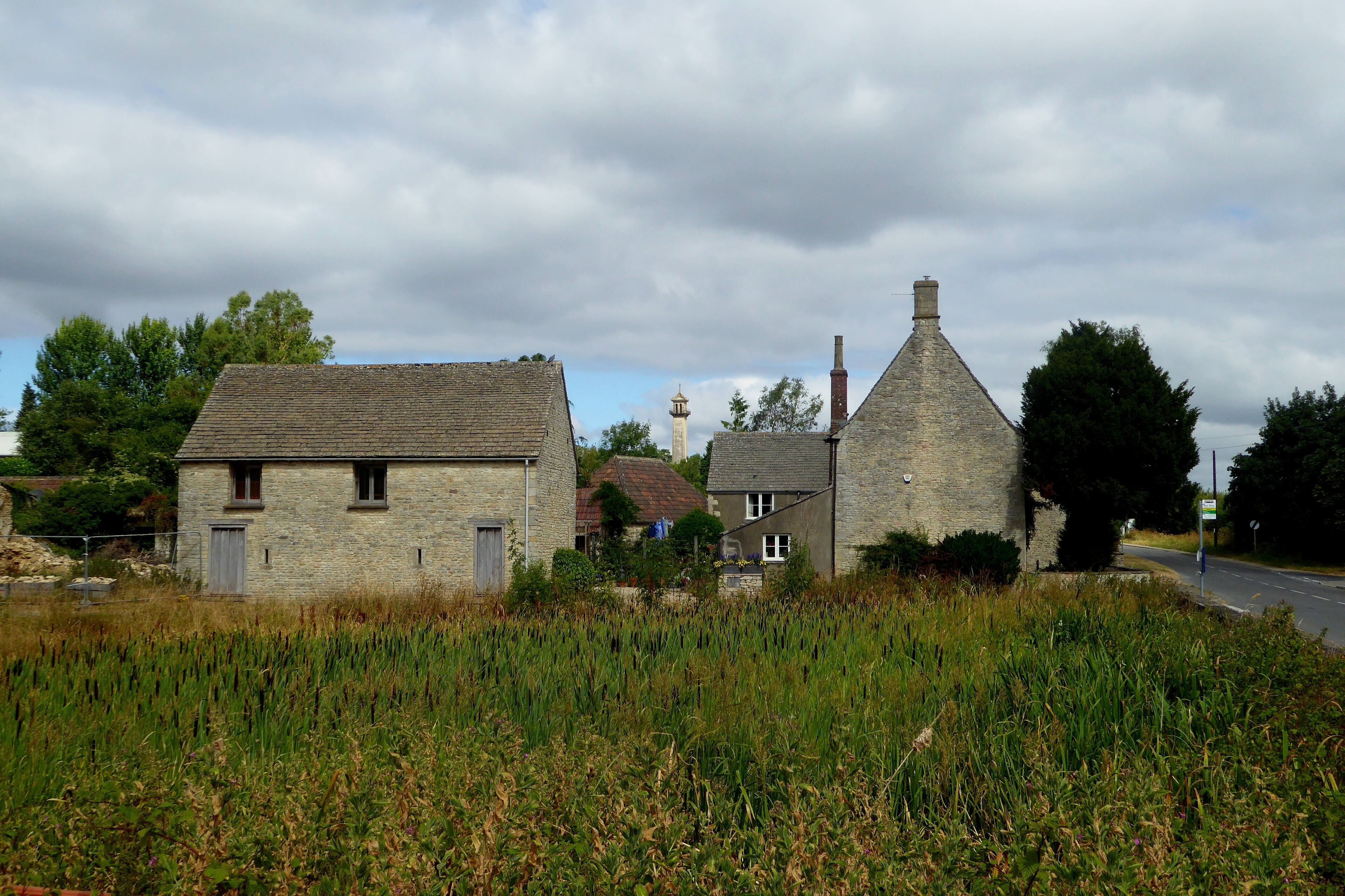 A rural village with stone houses, a church steeple, and a road.