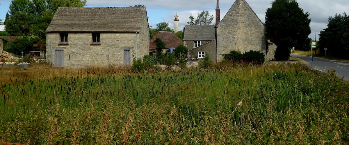 A rural village with stone houses, a church steeple, and a road.