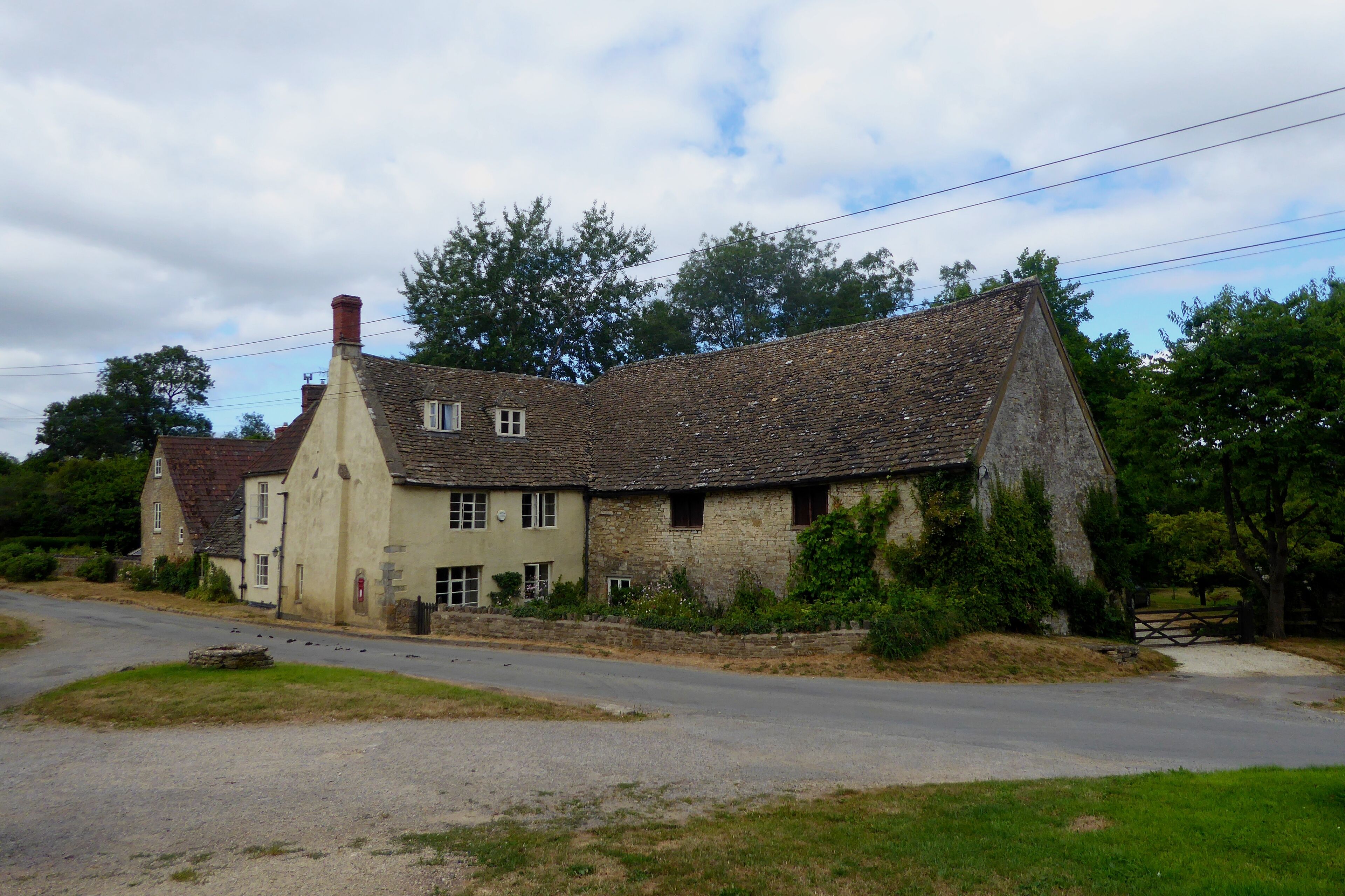 A house in the centre of Hawkesbury, Gloucestershire, as seen from near the Cotswolds Way route. To the left of the image is a small well.