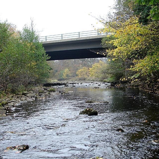 Greta Bridge (A66). In contrast to the elegant and much painted old bridge 67609, themodern A66 dual carriageway crosses the River Greta a short way downstream, and carries a constant stream of noisy traffic, giving only the barest glimpse of the river from the slow lane (just enough for a canoeist in the passenger seat to get a quick estimate of the level). The river level as seen here is way too low for paddling, as this is an exciting river that needs a lot of recent rain to bring it to life.