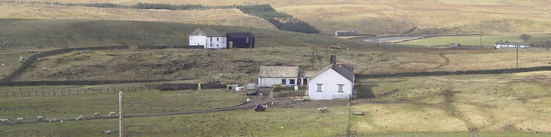 A rural landscape with rolling hills, a white house, and a stone wall.