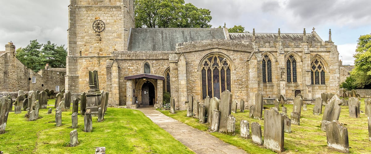 A historic church with a tall tower and a graveyard.