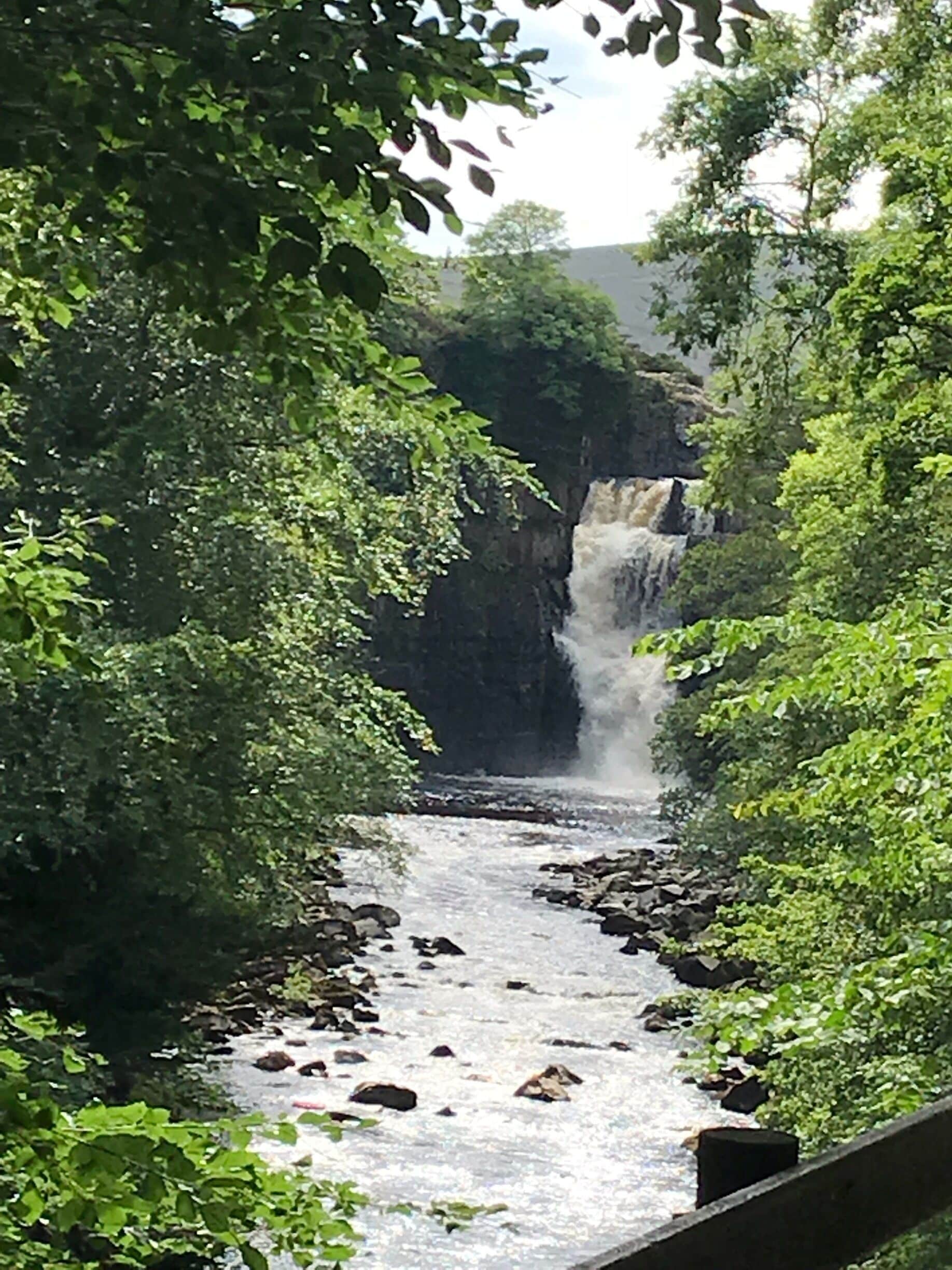 Un río fluye por un desfiladero rocoso, con una cascada al fondo.