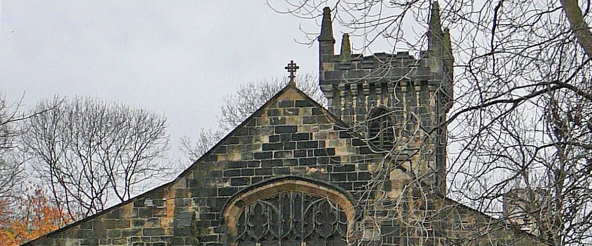 A historic stone church with a prominent arched window and a tower.