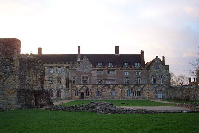 A historic stone building with a large lawn in front.