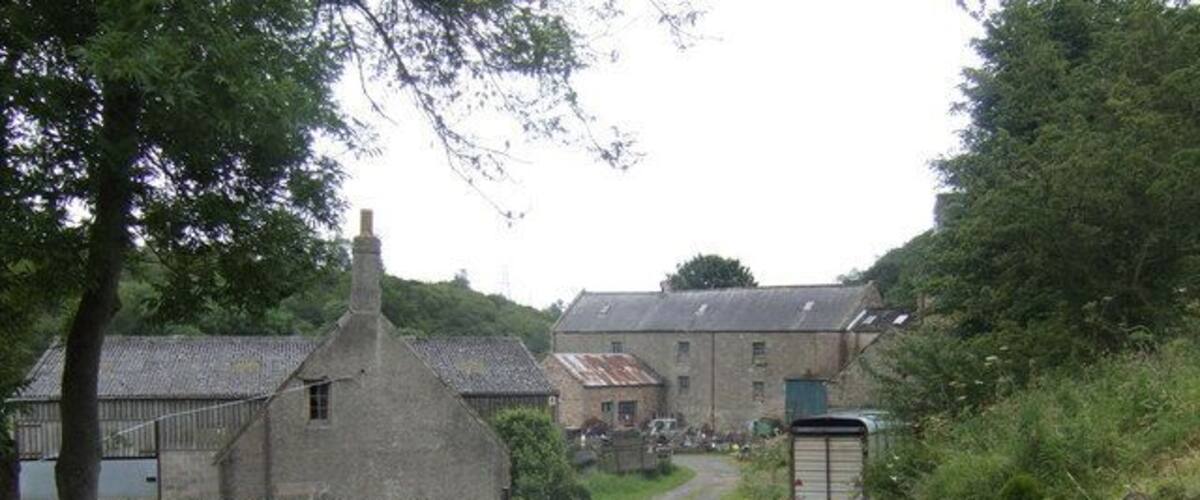 A rural road with stone buildings and a trailer on the side.
