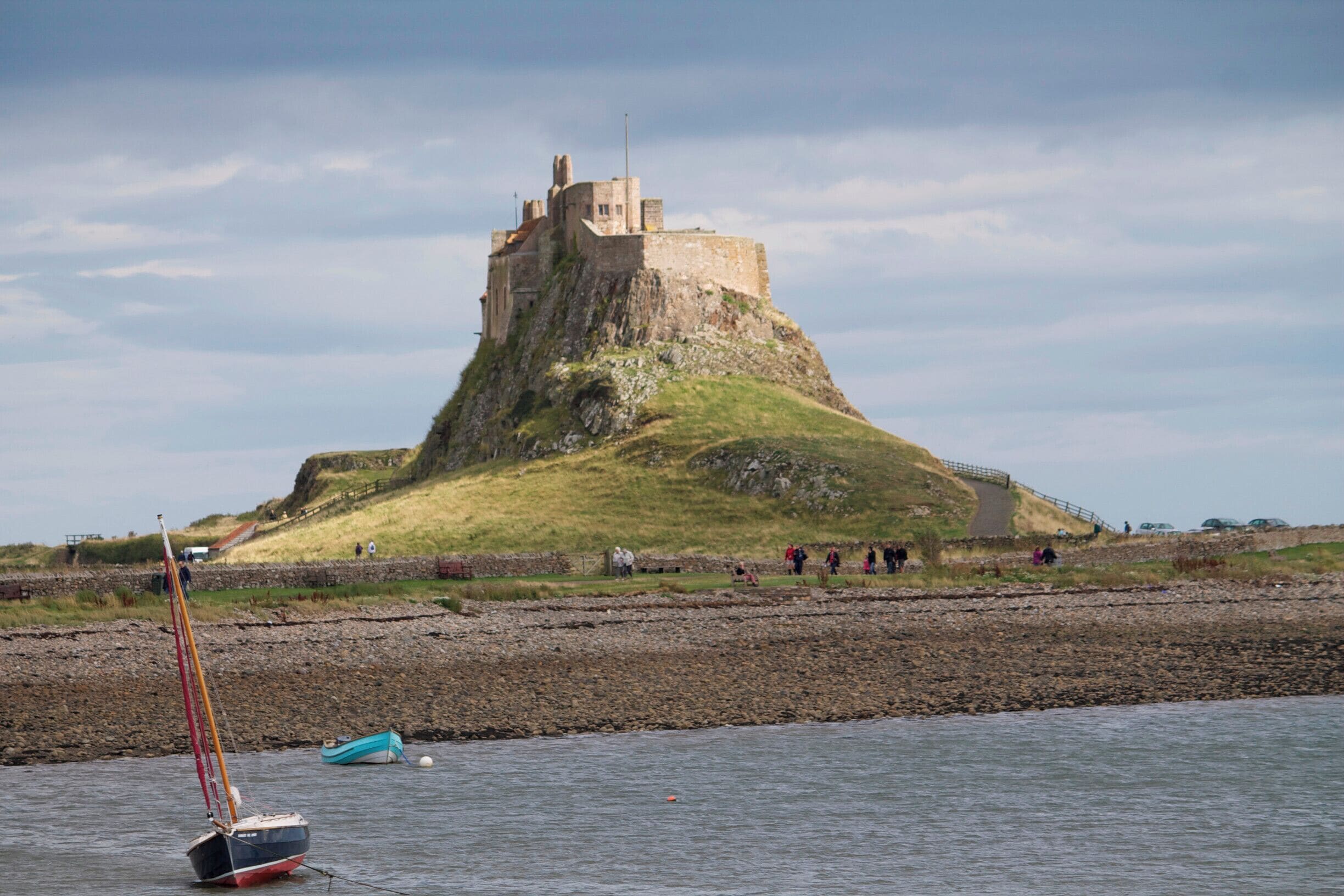 A castle on a grassy hill by the water.