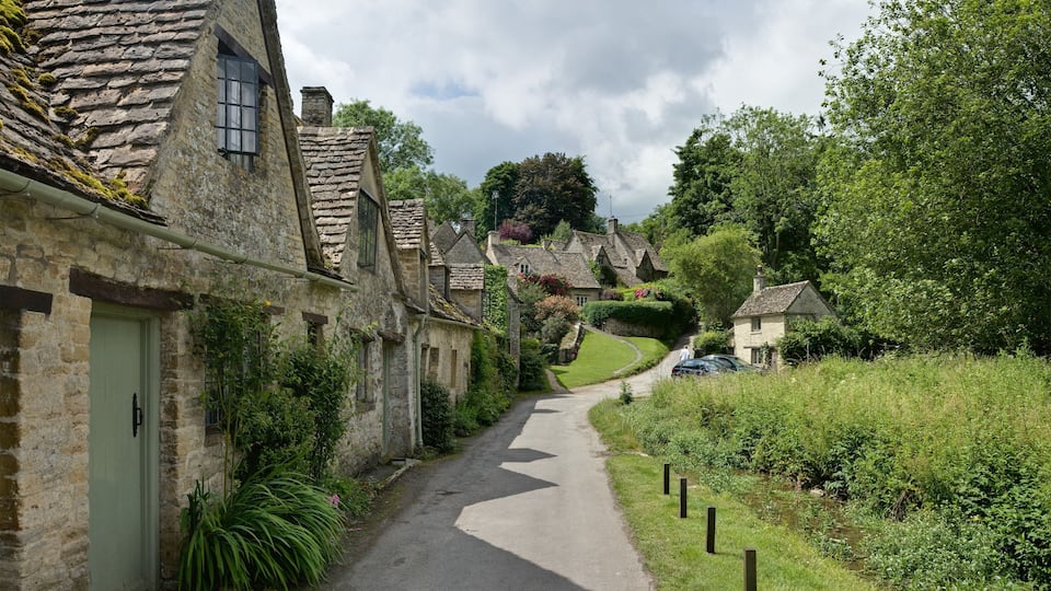 A narrow stone road in a rural village with traditional stone houses and lush greenery.