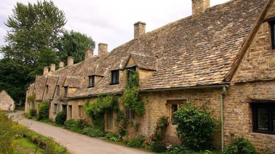 A row of stone cottages with thatched roofs and ivy growing on the walls.