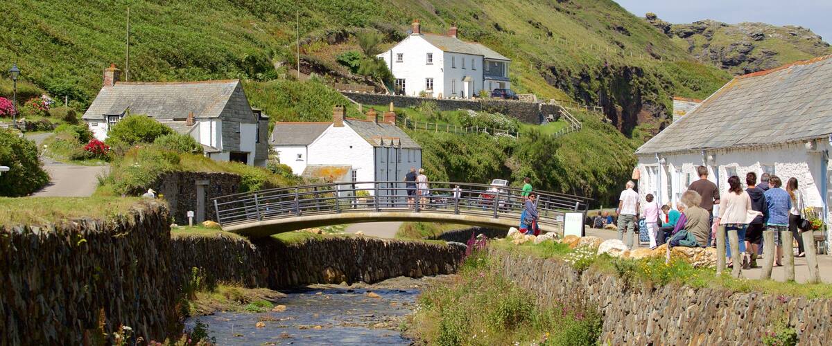 A stone bridge over a river, surrounded by lush greenery and houses on a hillside.
