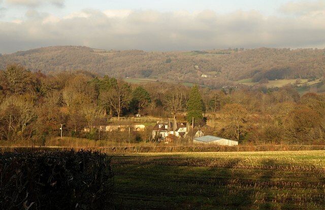 Towards Chapple from Stentiford Lane A view from Bovey Tracey Bridleway 10 across a stubble field. The farm at Chapple is a few metres across an eastinbg gridline into SX8077, and the barn straddles the line. Beyond is part of Colehayes Plantation. In the distance are the hills around Shaptor and Stonelands on the far side of the Bovey valley.