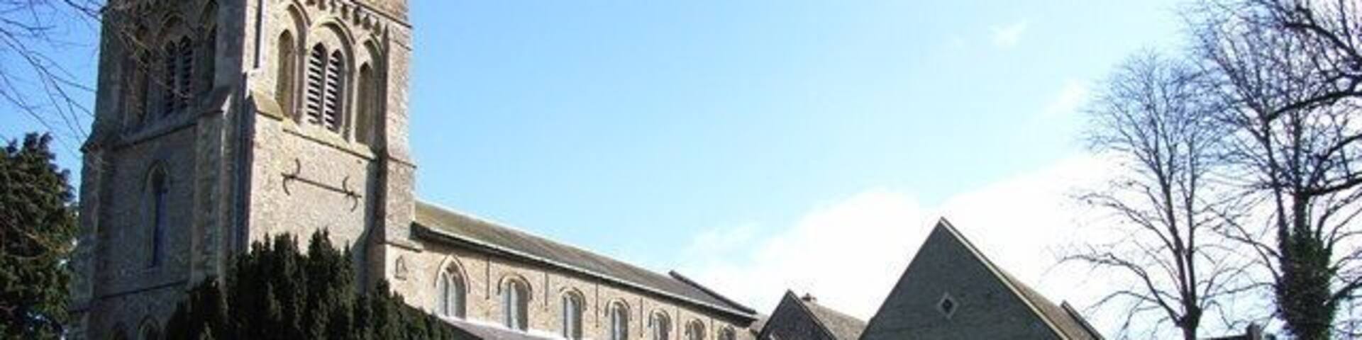 A church with a tall tower and a smaller building with a pointed roof.
