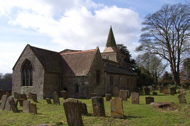 A church with a pointed steeple and a graveyard with headstones.