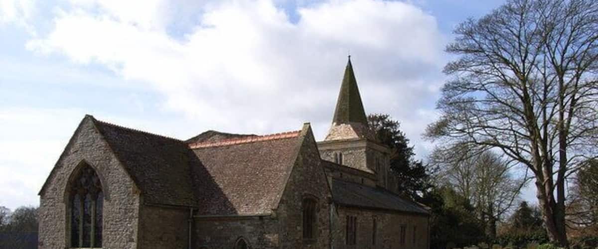 A church with a pointed steeple and a graveyard with headstones.