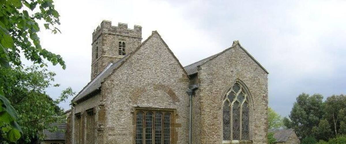 A stone church with a prominent arched window and a tower.