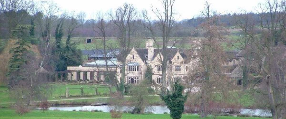 A large stately house with a pond in the foreground.