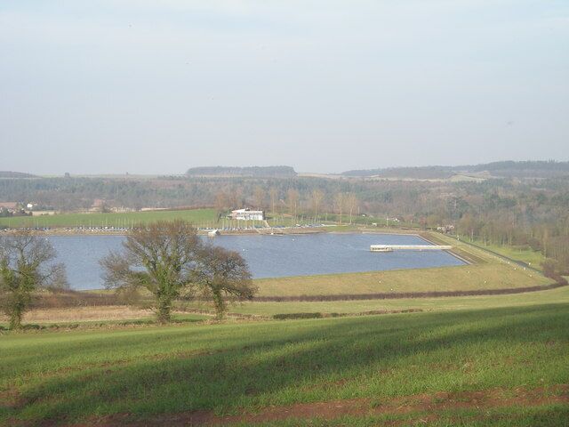 A lake with a small island, a white building, and a dock.