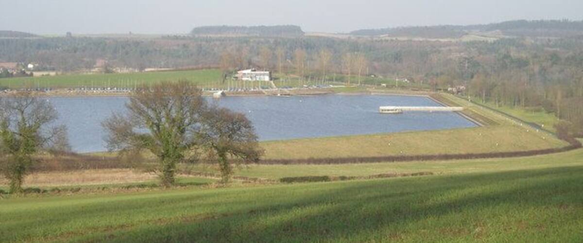 A lake with a small island, a white building, and a dock.