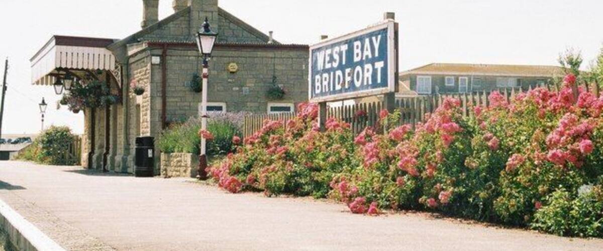 A building with a sign reading "West Bay Bridgport" and a flower garden in front.