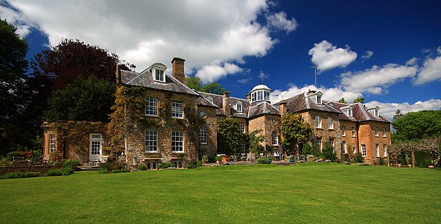 A large stone building with a green lawn in front.