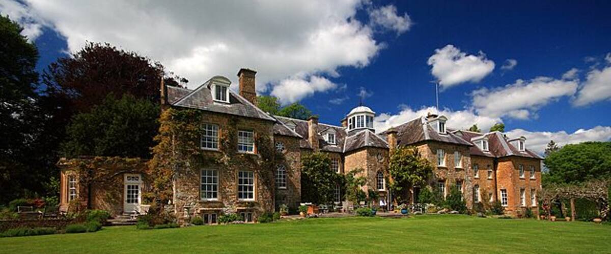 A large stone building with a green lawn in front.