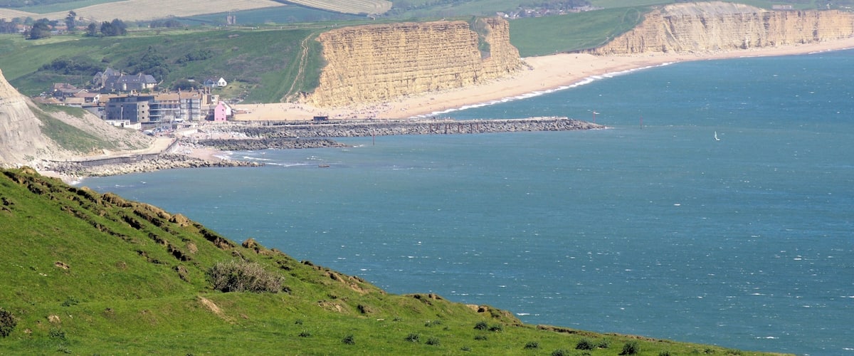 Un paisaje costero con acantilados, una playa y un pequeño pueblo con edificios.