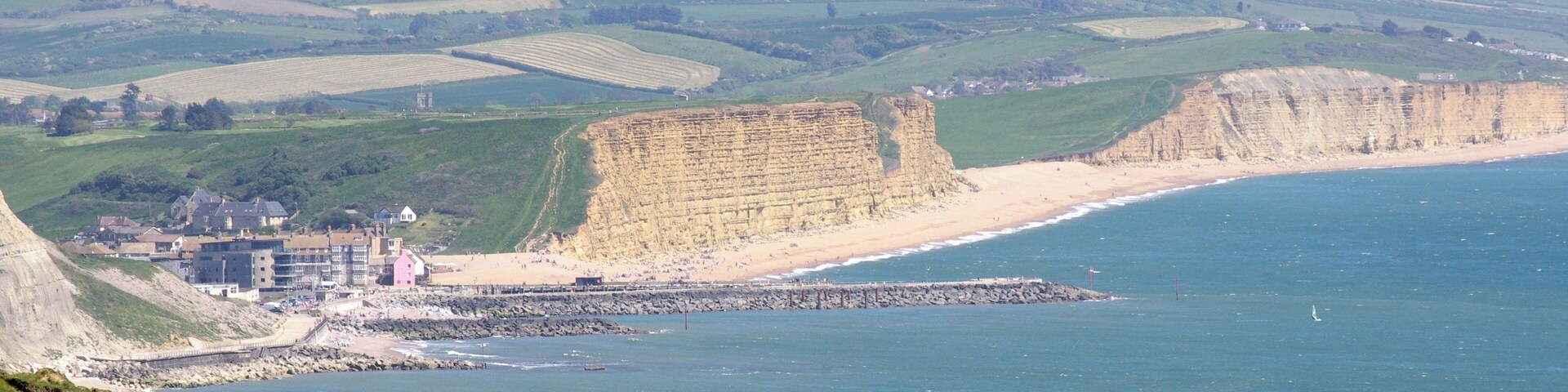 Un paisaje costero con acantilados, una playa y un pequeño pueblo con edificios.