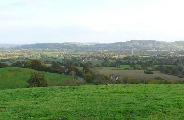 Countryside near Marshwood View SSE across the grid square from the B3165 in Marshwood. The road in the centre is the minor road that runs south from Marshwood to Sminhay Farm. In the middle distance is Marshwood Vale with the coastal hills between Charmouth and Bridport just beyond, including Stonebarrow and Golden Cap on the extreme right.
