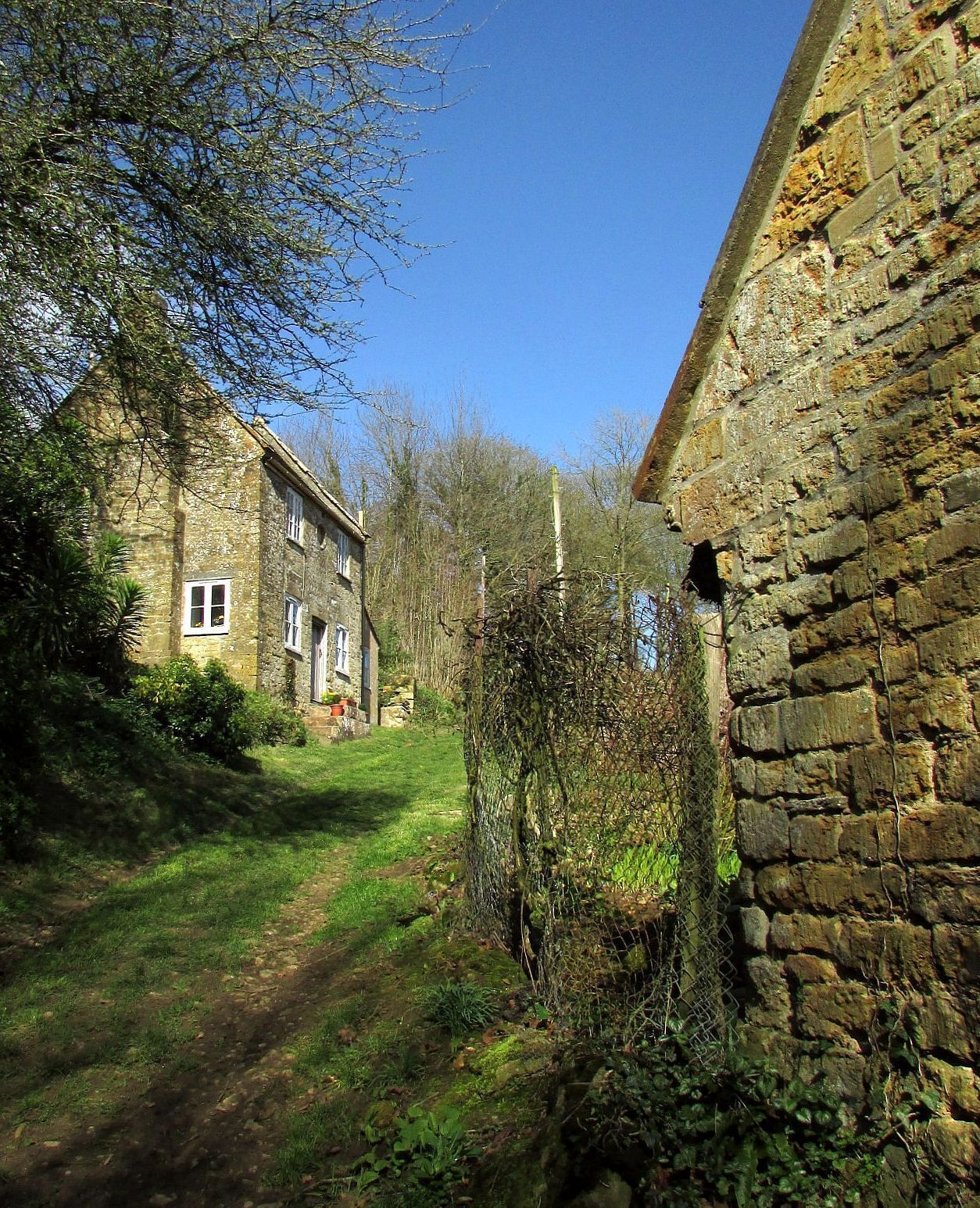 A stone building with a garden path leading to a house.