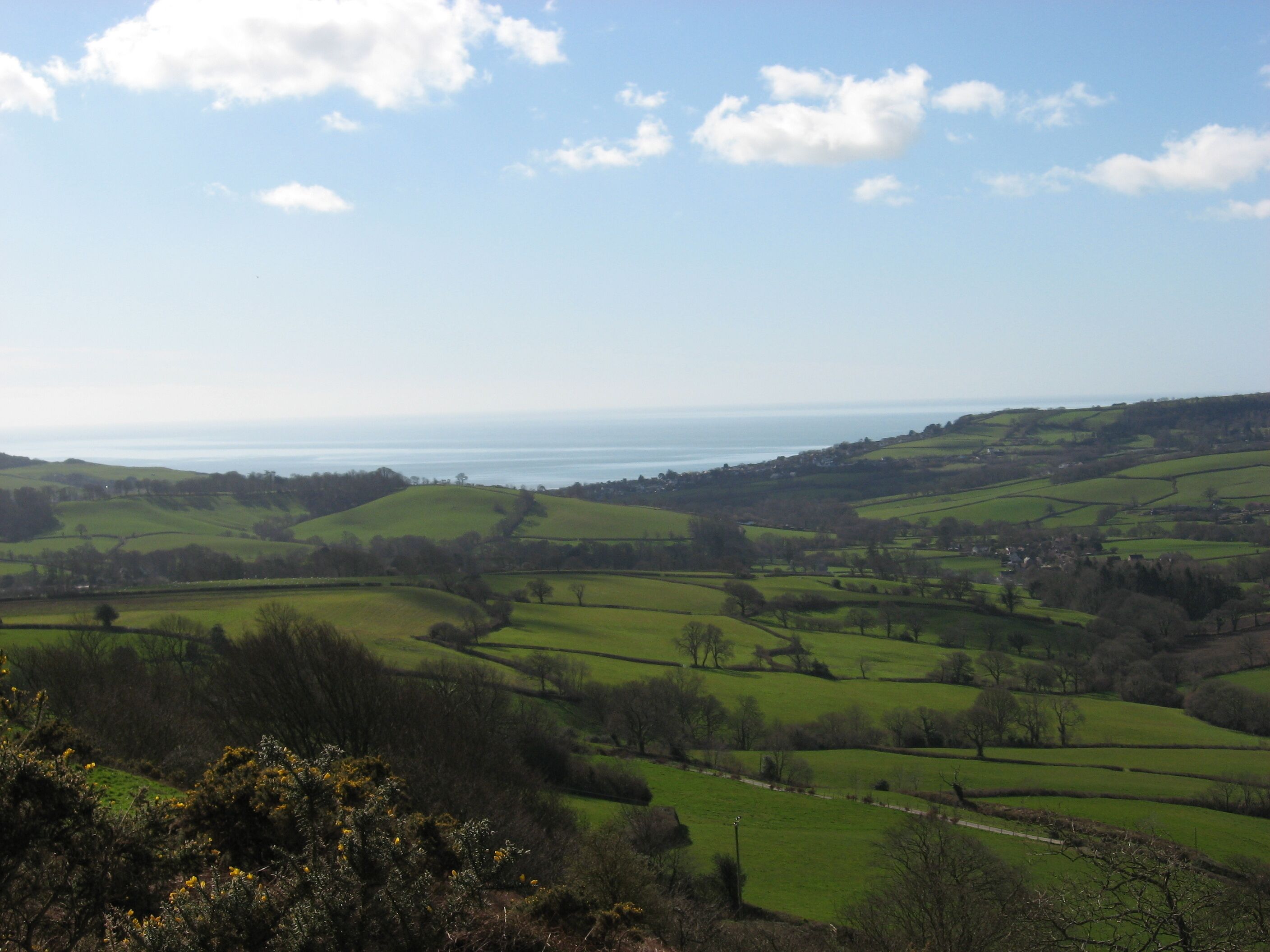 Rolling green hills, a distant sea, and a clear sky.