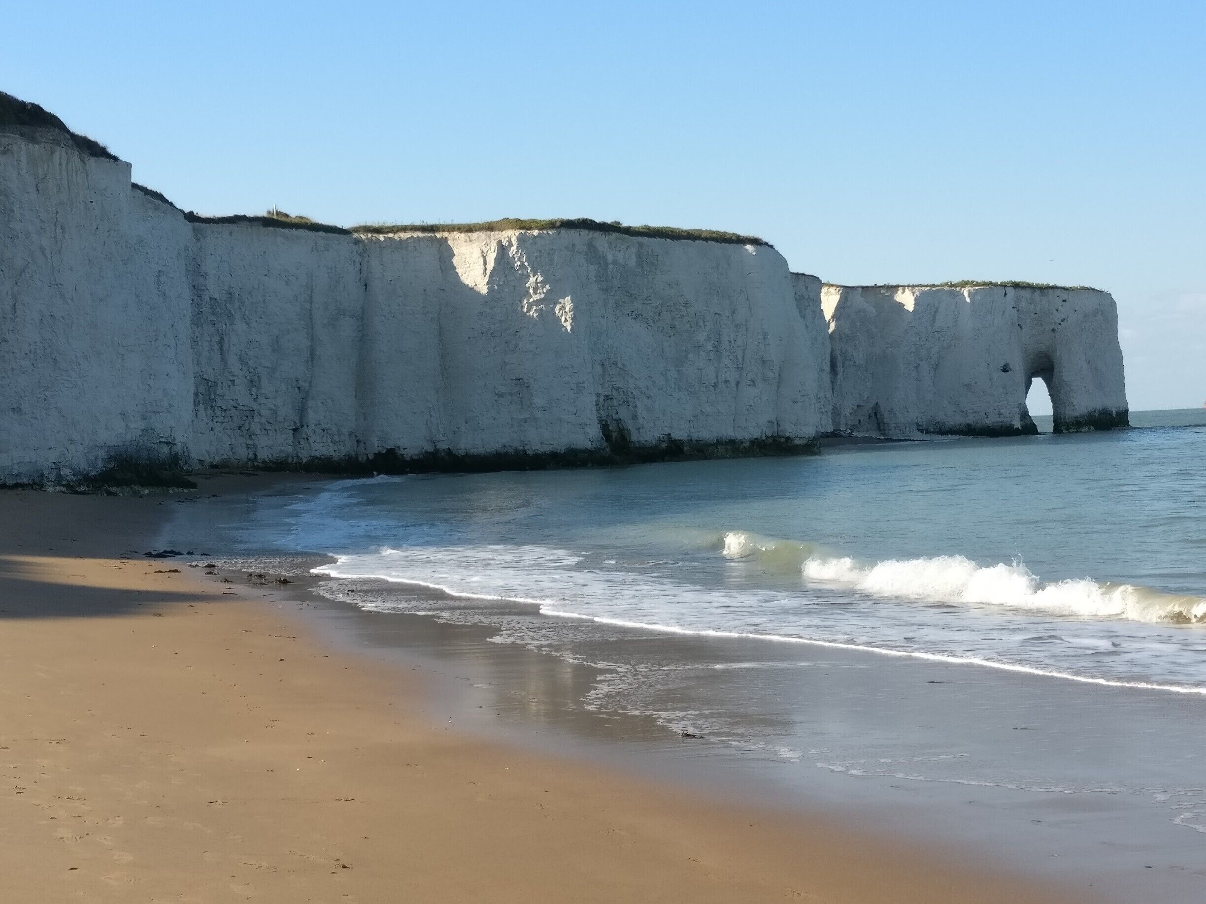 A beach with white cliffs and a sea arch.