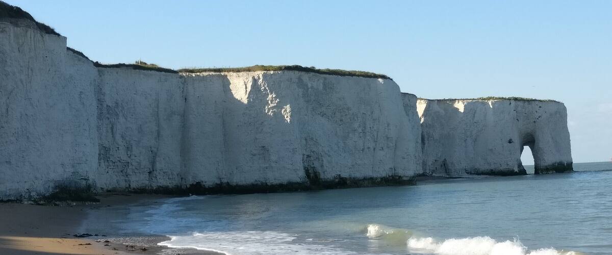 A beach with white cliffs and a sea arch.