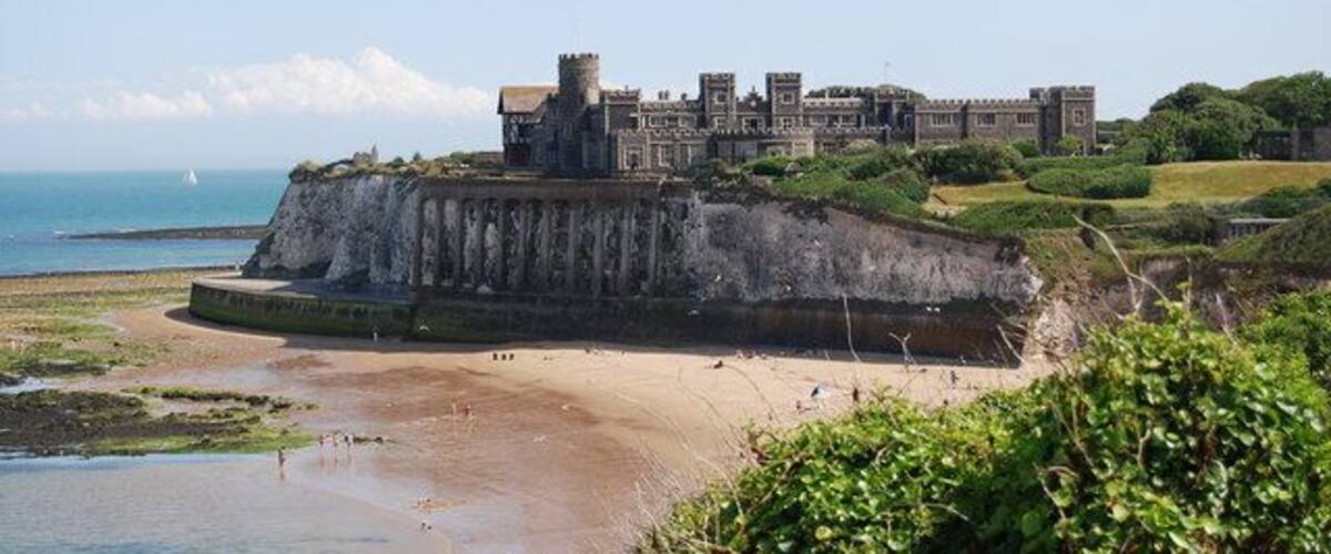 A coastal castle on a cliff overlooking the sea.