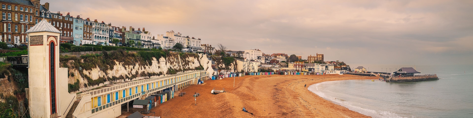 Panoramic image of Viking Bay, Broadstairs, UK on a mild winter day. The elevator shaft to the beach and the row of beach huts can be seen along with the pier.
