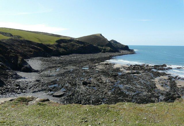 A rocky coastline with a grassy hill in the background.