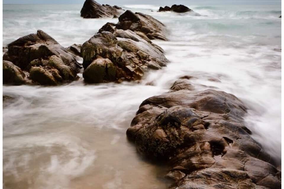 Uma costa rochosa com ondas quebrando nas pedras.