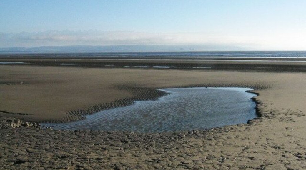Berrow Flats Early evening with a rising tide. The setting sun provides dramatic lighting across the windswept sands while on the horizon is Exmoor and Hinkley Point Nuclear Power Station.