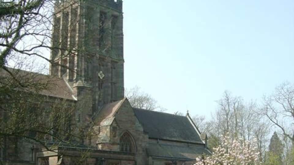 A historic church with a tall tower and a blooming tree in front.