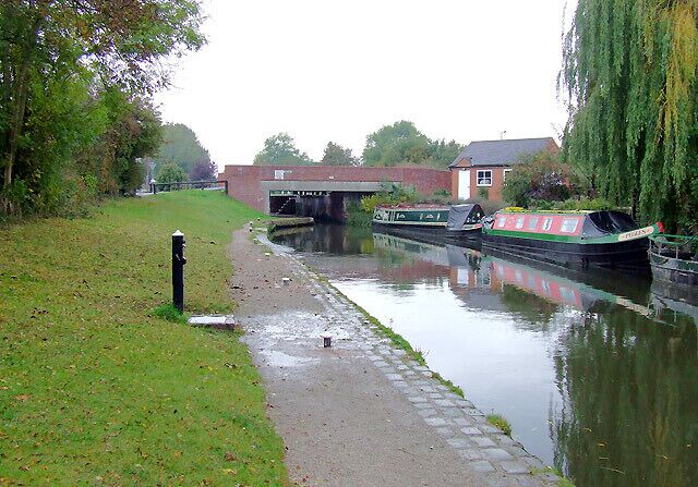Trent and Mersey Canal at Barton Turn, Staffordshire. On the Trent and Mersey Canal, Barton Turn Bridge and Lock are ahead. The black pillar by the towpath is a water point for the use of boaters.