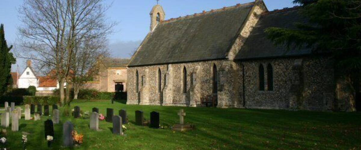 A church with a stone facade and a bell tower, surrounded by a cemetery with headstones.
