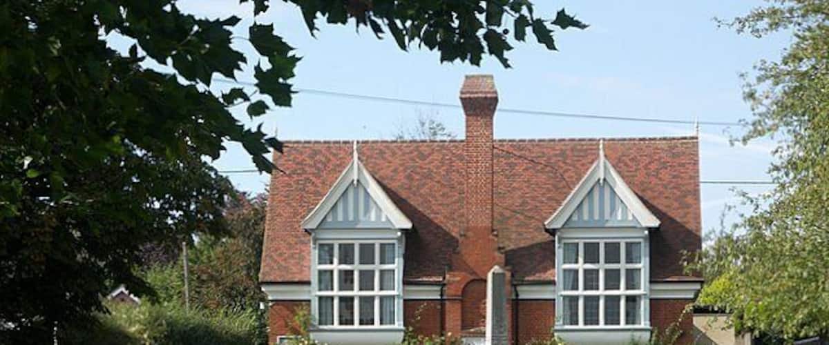 A brick house with two gabled windows and a central statue.