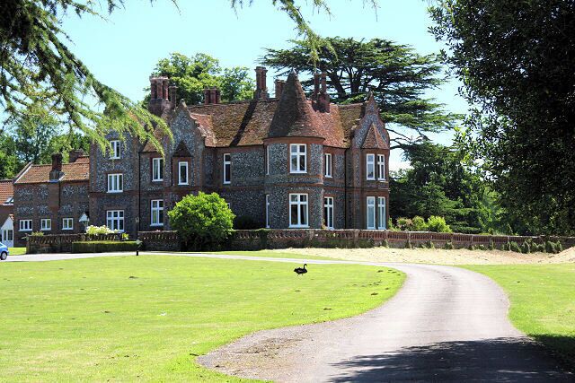 A large, historic stone building with a curved driveway and a well-maintained lawn.