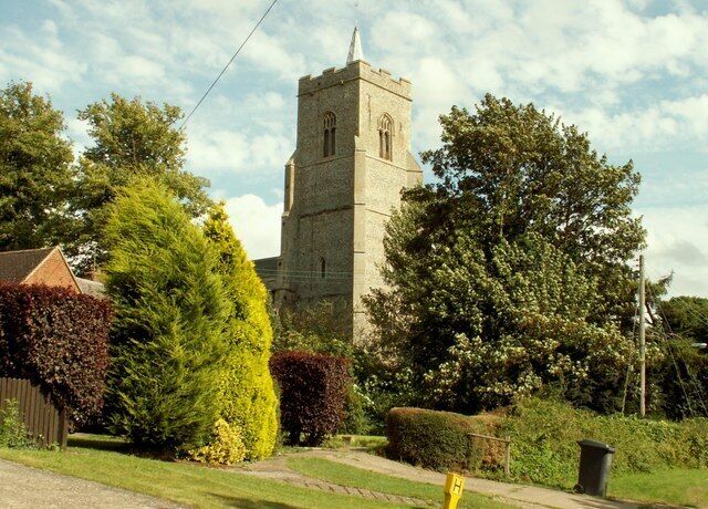 A church with a tall tower, surrounded by well-maintained hedges and trees.